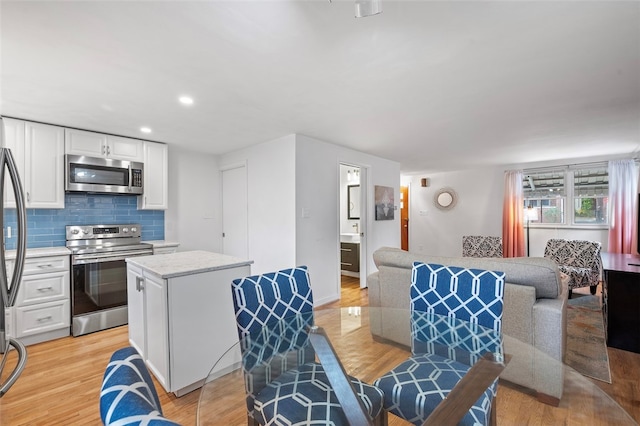 kitchen featuring white cabinets, stainless steel appliances, a center island, and light hardwood / wood-style flooring