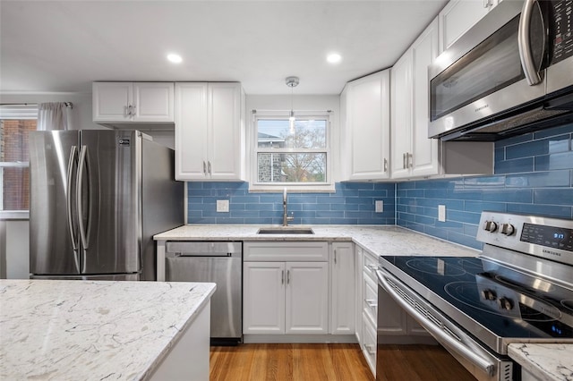 kitchen with decorative light fixtures, white cabinetry, appliances with stainless steel finishes, and sink