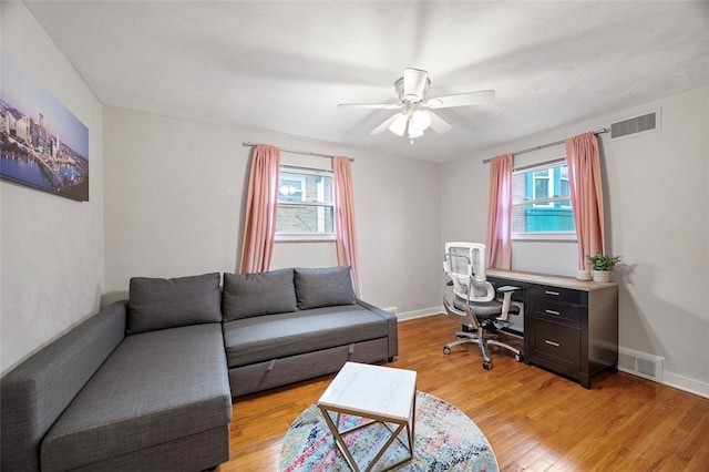 office space featuring a wealth of natural light, ceiling fan, and light wood-type flooring