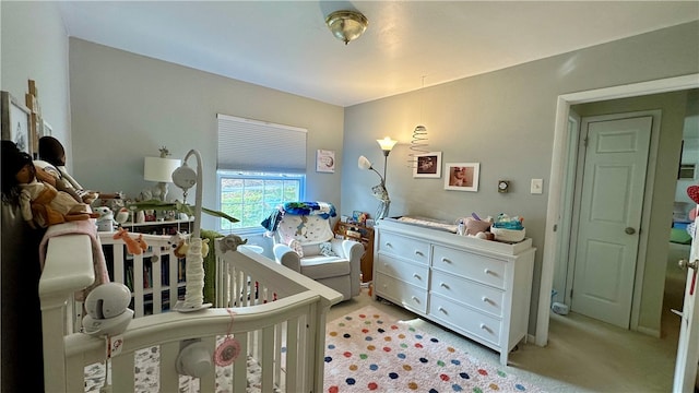 bedroom featuring light colored carpet and a nursery area