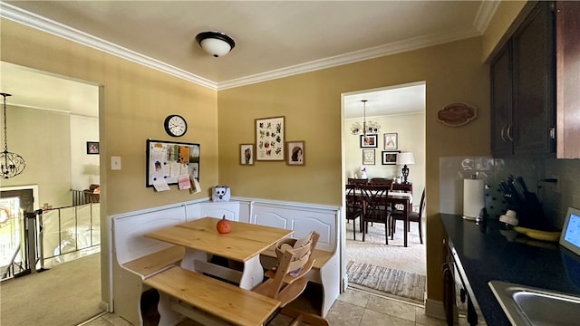 carpeted dining area featuring sink, a chandelier, and ornamental molding