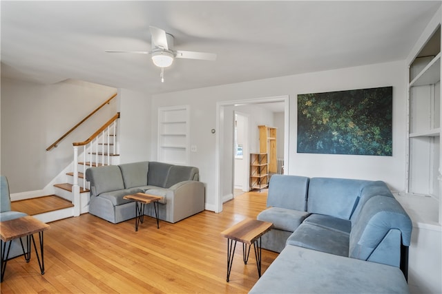 living room featuring built in features, ceiling fan, and light hardwood / wood-style floors