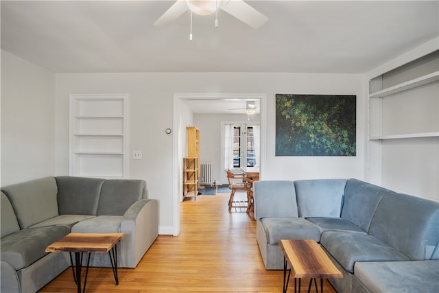 living room featuring light hardwood / wood-style flooring, radiator heating unit, ceiling fan, and built in features