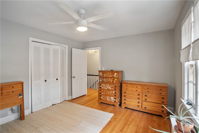 bedroom featuring hardwood / wood-style flooring, multiple windows, ceiling fan, and a closet