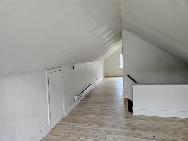 additional living space with baseboard heating, lofted ceiling, and light wood-type flooring