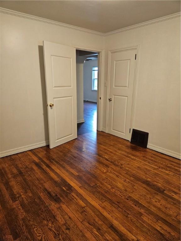 empty room with dark wood-type flooring and crown molding