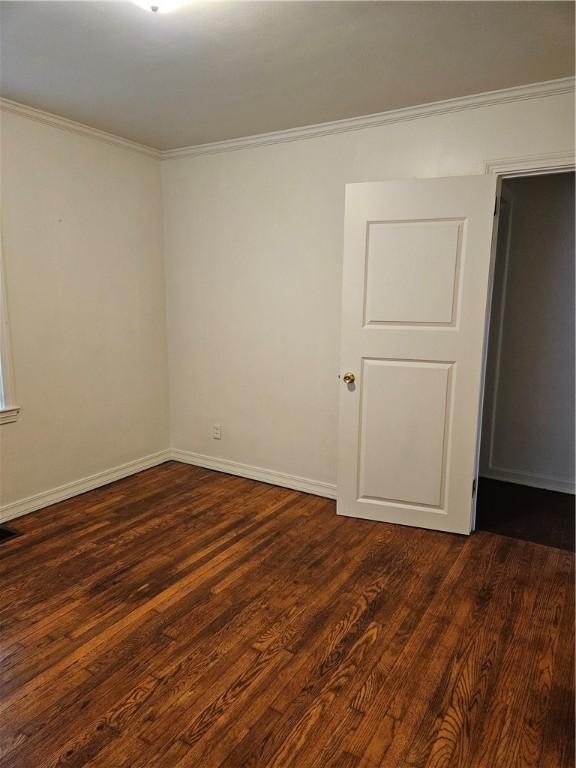 spare room featuring dark hardwood / wood-style flooring and ornamental molding