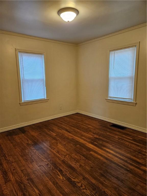 empty room featuring dark hardwood / wood-style floors and ornamental molding