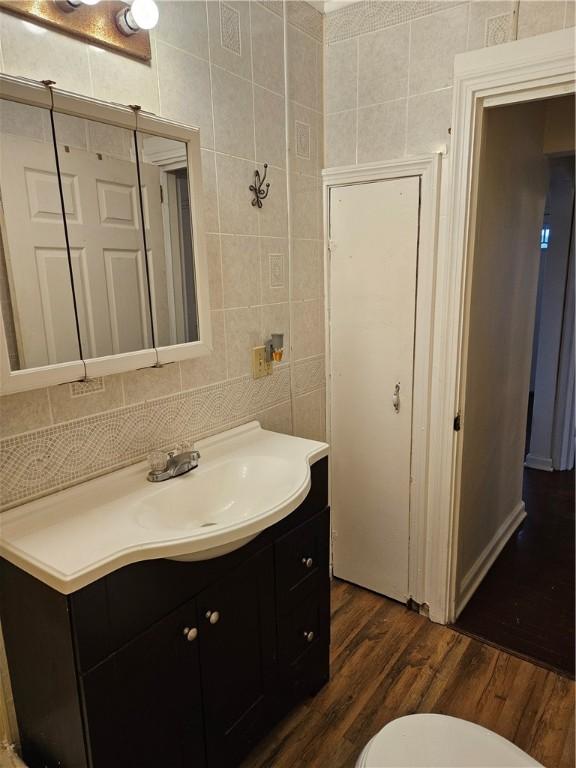 bathroom featuring hardwood / wood-style floors, toilet, vanity, and tile walls