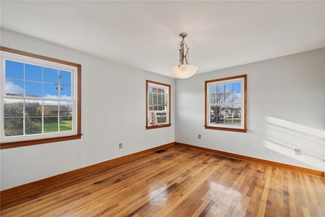 unfurnished room featuring hardwood / wood-style flooring, baseboards, and cooling unit