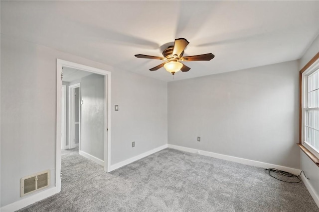 carpeted empty room featuring a ceiling fan and baseboards