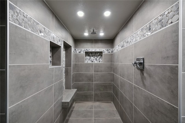 bathroom featuring tile walls, tile patterned flooring, and a tile shower