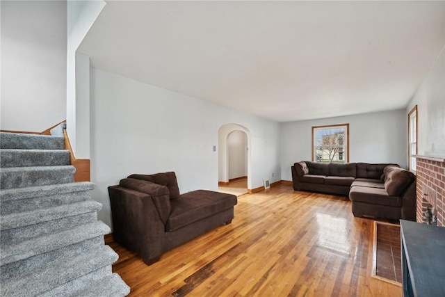living area with arched walkways, light wood-style floors, and stairway