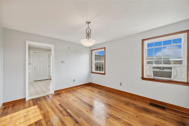 unfurnished room with cooling unit, light wood-type flooring, and baseboards
