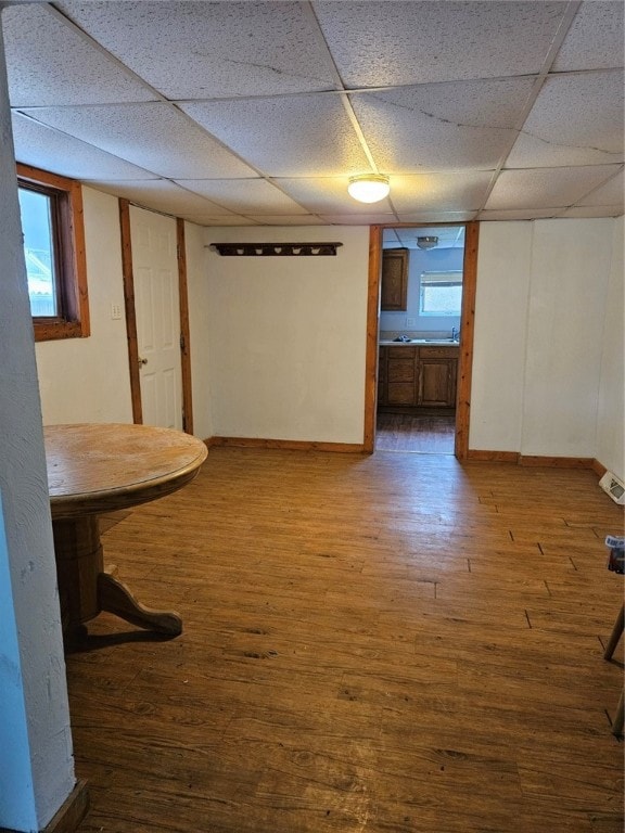 basement featuring a paneled ceiling and hardwood / wood-style flooring