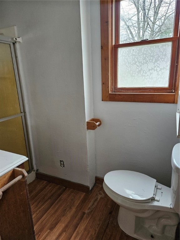 bathroom with toilet, an enclosed shower, and hardwood / wood-style flooring