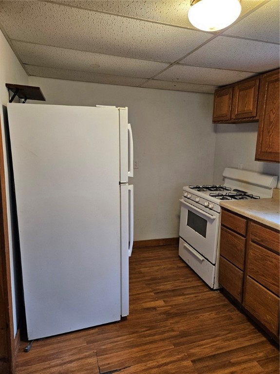 kitchen featuring a drop ceiling, dark wood-type flooring, and white appliances