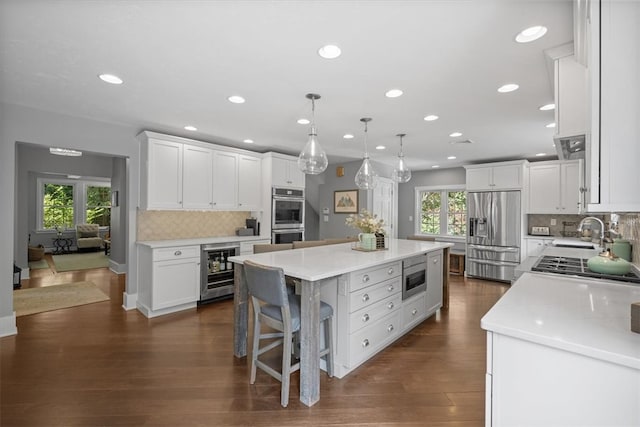 kitchen with white cabinetry, stainless steel appliances, a healthy amount of sunlight, and a center island