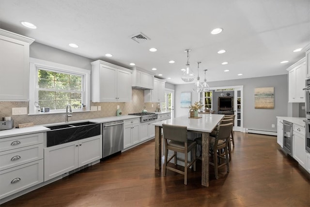 kitchen with stainless steel appliances, white cabinets, and dark wood-type flooring