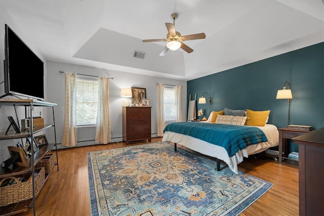 bedroom with hardwood / wood-style flooring, ceiling fan, and a tray ceiling