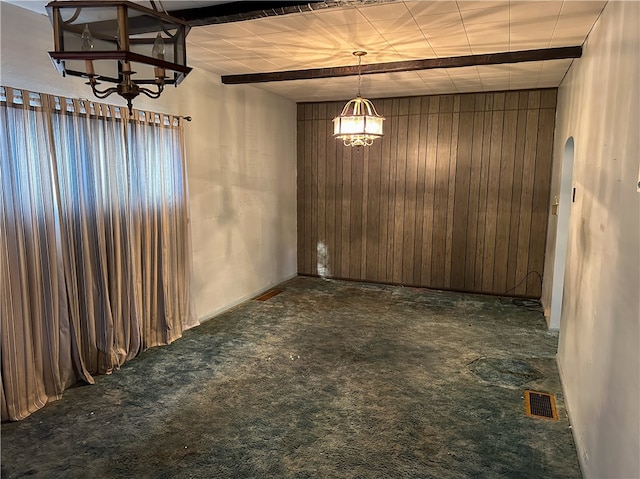 unfurnished dining area with wood walls, beamed ceiling, and dark carpet