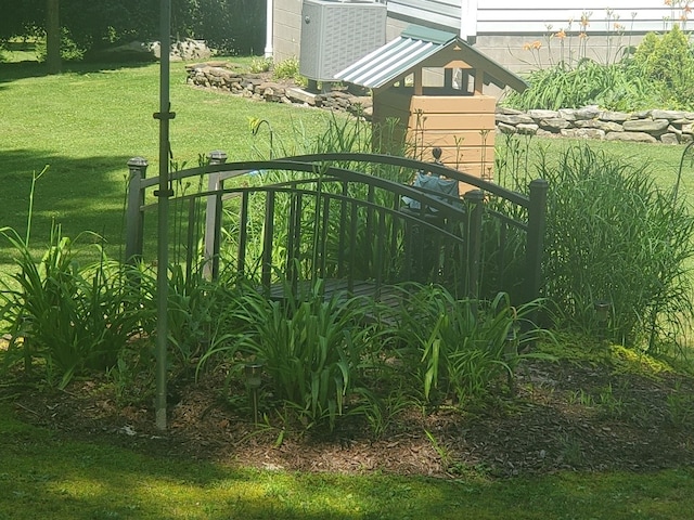 view of gate with a lawn and central air condition unit