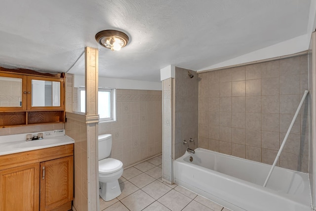 full bathroom with toilet, vaulted ceiling, tile walls, tile patterned flooring, and bathing tub / shower combination