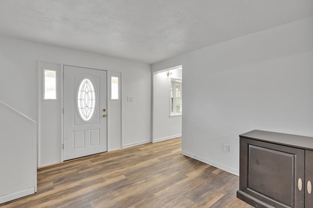 entrance foyer with a textured ceiling, a wealth of natural light, and dark hardwood / wood-style floors