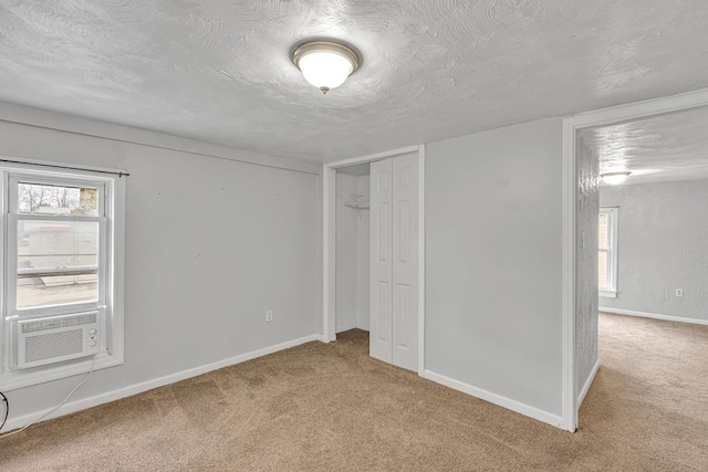 unfurnished bedroom with light colored carpet, a textured ceiling, a closet, and cooling unit