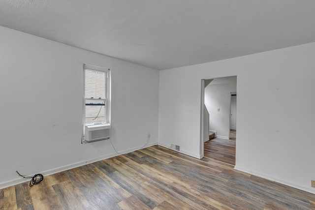 empty room featuring dark hardwood / wood-style floors, a textured ceiling, and cooling unit