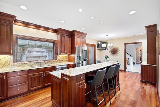 kitchen with appliances with stainless steel finishes, pendant lighting, decorative backsplash, light hardwood / wood-style floors, and a center island