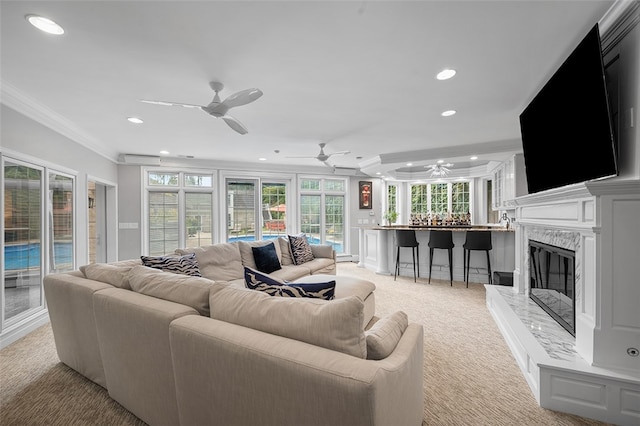 living room with a premium fireplace, light colored carpet, ceiling fan, and crown molding