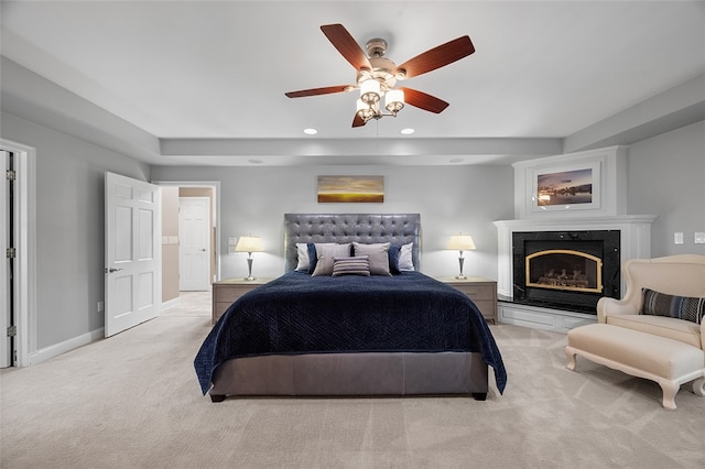 bedroom featuring a fireplace, ceiling fan, and light colored carpet