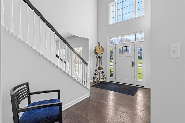 foyer with dark hardwood / wood-style flooring, a healthy amount of sunlight, and a towering ceiling