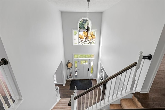 entrance foyer featuring a textured ceiling, wood-type flooring, a healthy amount of sunlight, and an inviting chandelier