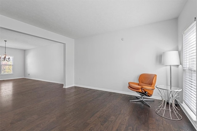 unfurnished room featuring a textured ceiling, dark hardwood / wood-style floors, and a chandelier