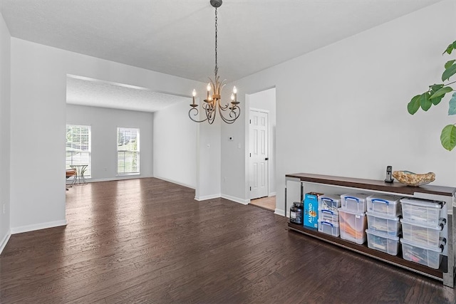 dining room featuring dark wood-type flooring, a textured ceiling, and a notable chandelier