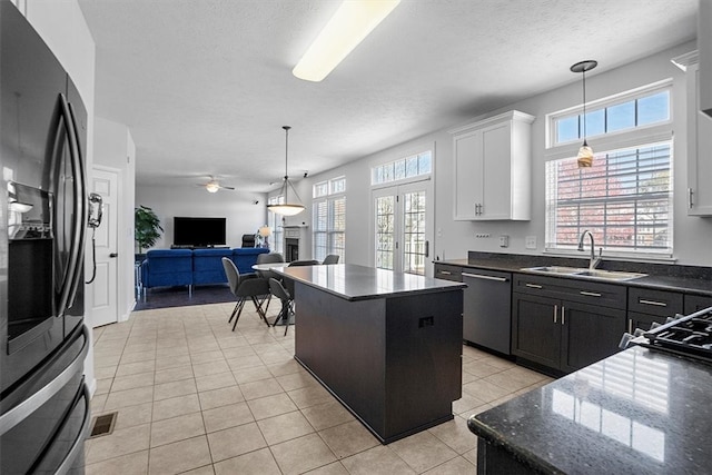 kitchen with white cabinetry, black fridge, sink, ceiling fan, and a center island