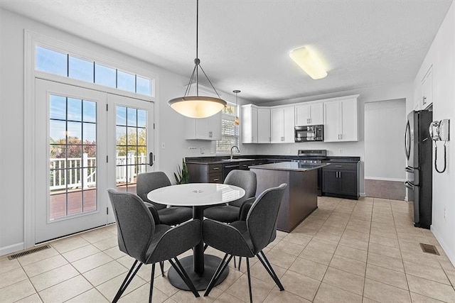 dining area with a textured ceiling, light tile patterned floors, and sink