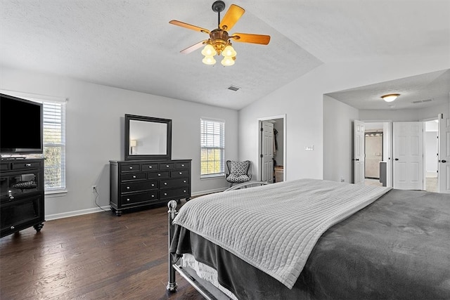 bedroom featuring a walk in closet, a textured ceiling, vaulted ceiling, dark wood-type flooring, and ceiling fan