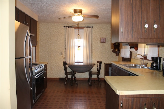 kitchen with stainless steel appliances, kitchen peninsula, dark brown cabinetry, sink, and ceiling fan