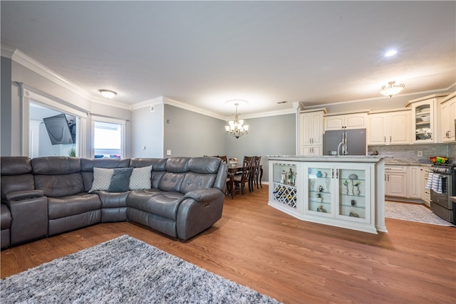 living room featuring ornamental molding, light hardwood / wood-style flooring, and an inviting chandelier