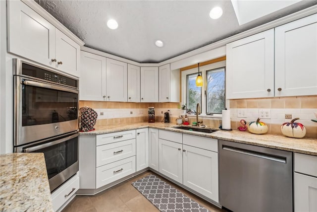 kitchen with white cabinetry, appliances with stainless steel finishes, sink, and backsplash