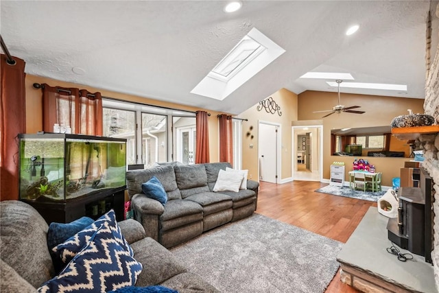 living room with ceiling fan, lofted ceiling with skylight, and hardwood / wood-style floors