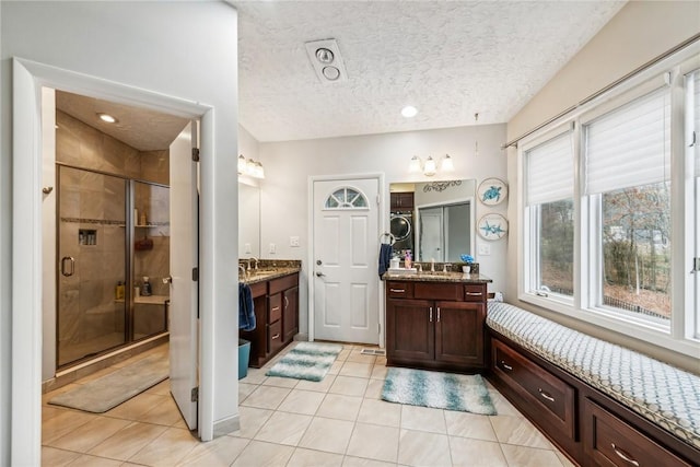 bathroom with vanity, a shower with shower door, tile patterned floors, and a textured ceiling