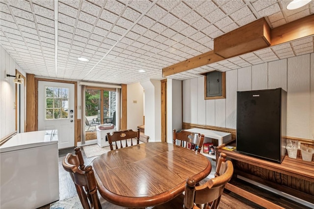 dining room featuring electric panel and wood walls