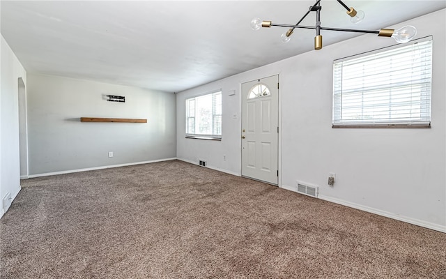 carpeted entrance foyer featuring a chandelier