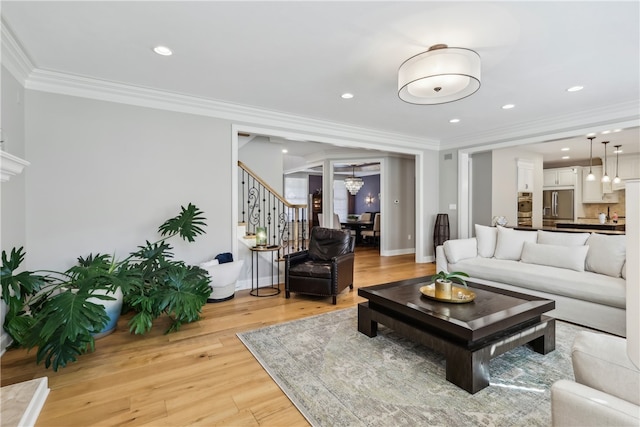 living room featuring ornamental molding, light wood-type flooring, and an inviting chandelier