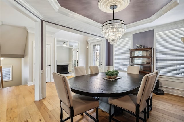 dining area featuring ornamental molding, light hardwood / wood-style floors, and a raised ceiling