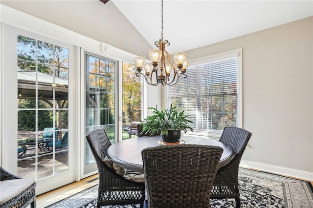 dining space featuring hardwood / wood-style flooring, a chandelier, and vaulted ceiling